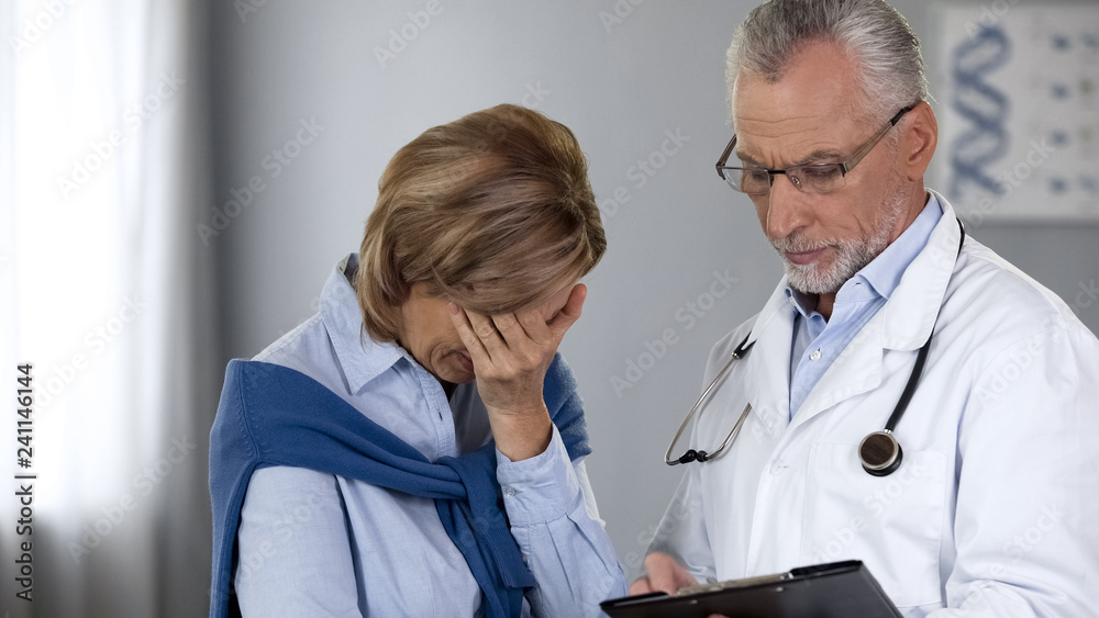 Doctor showing unhappy woman bad test results, cancer treatment, oncology Doctor showing unhappy woman bad test results, cancer treatment, oncology
