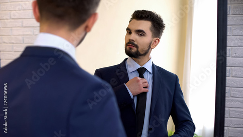 Man in business suit looking at mirror reflection, ready for work interview photo