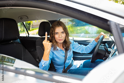 Young woman making obscene gestures while driving on the road © Snapic.PhotoProduct