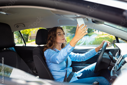 Young businesswoman taking selfie while driving a car © Snapic.PhotoProduct
