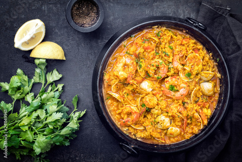 Traditional Portuguese arroz caldoso con almejas with shrimps and calm as top view in a cast-iron pot