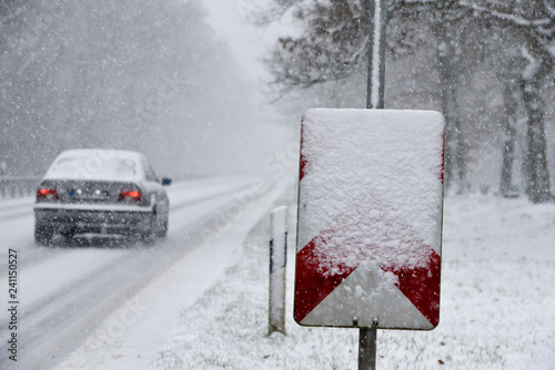 Auto fährt auf zugeschneiter Straße photo