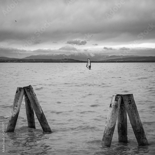 Dezember Surfer auf dem Neusiedlersee vor dem Schneeberg in schwarzweiss photo