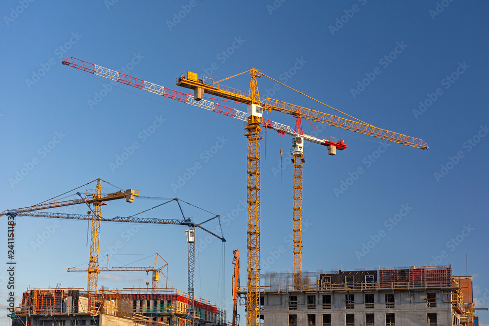 Building industry landscape - large cranes on the construction site on a blue sky background.