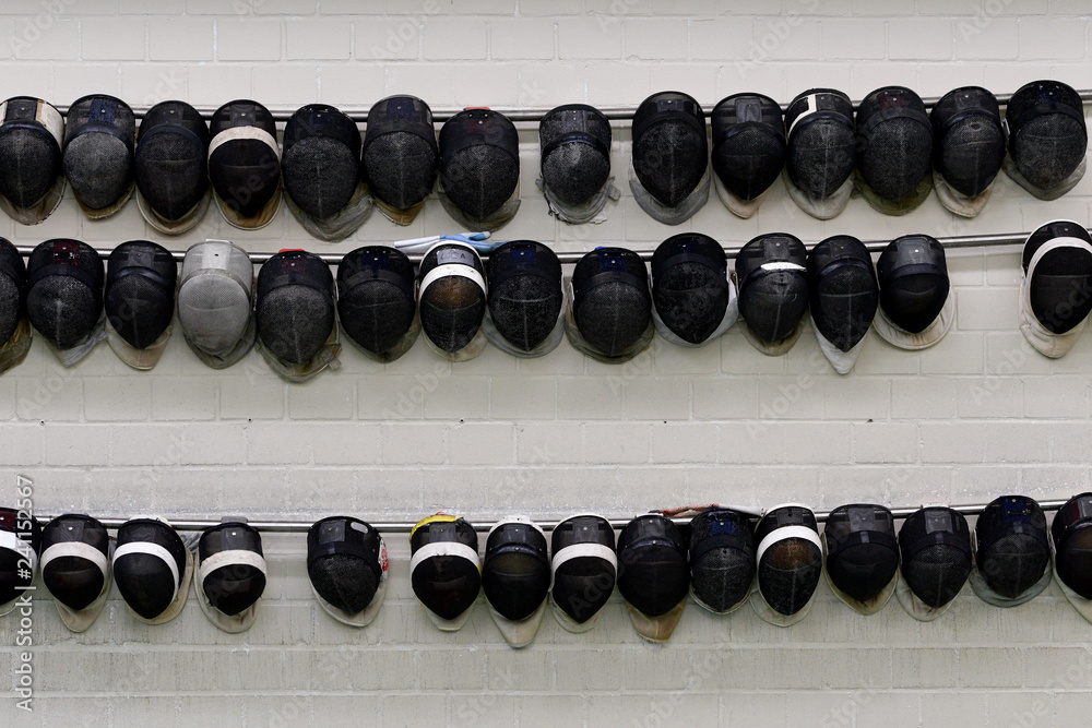 Fechthelme hängen aufgereiht an einer Wand. Fechthelme hängen aufgereiht an einer Wand.
