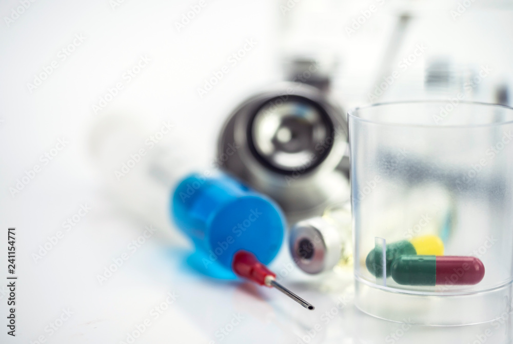 Plastic glass with daily medication along with to a syringe, conceptual image Plastic glass with daily medication along with to a syringe, conceptual image