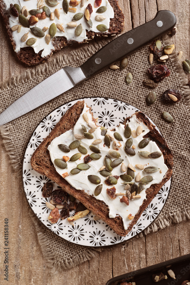 top view of slice of wholemeal bread spread with cheese and cover of sunflower seeds