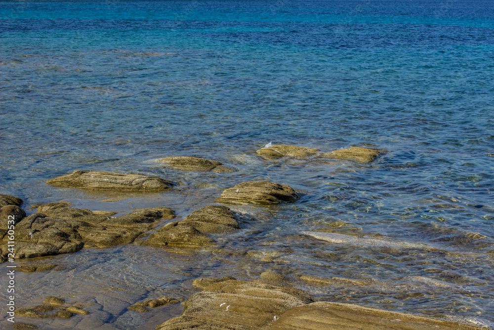 Mediterranean sea local scenic rocky coast shoreline with stone from under water and vivid blue ripple surface