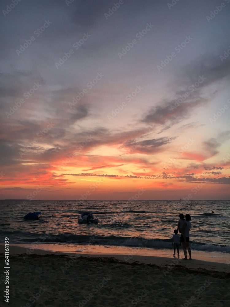 A family is looking at the sunset from the Platja d’Illetes, Formentera island, Spain.