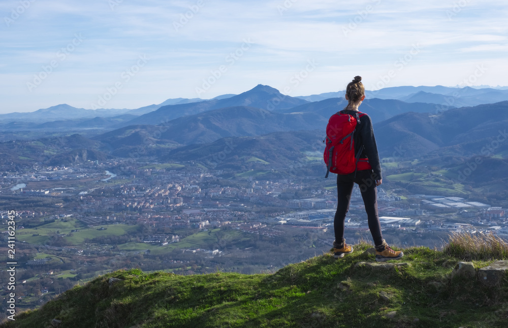 The girl at mountain top. Successful woman backpacker looking at the city.