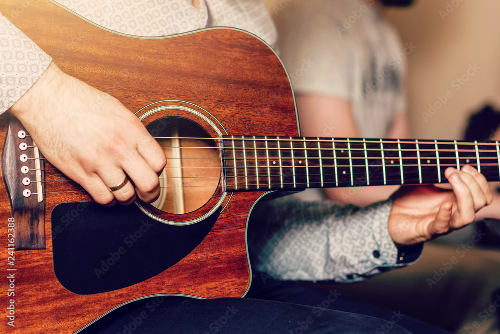 Fototapeta Young musician playing acoustic guitar close up