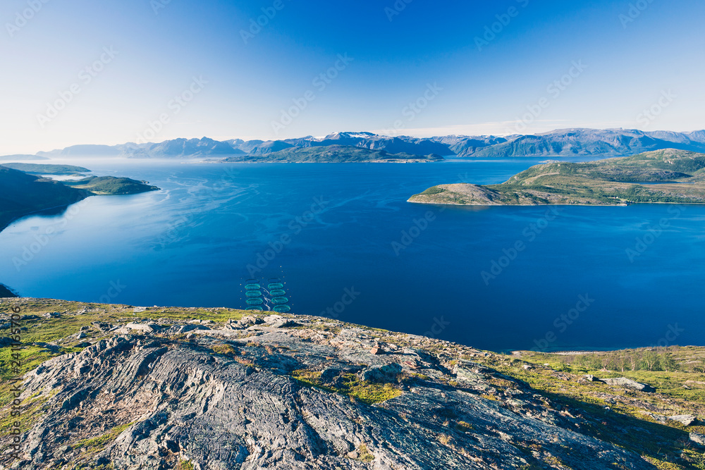 Salmon farms in Norwegian fjord, near Alta. View from high mountain peak at sunny day. Salmon farms in Norwegian fjord, near Alta. View from high mountain peak at sunny day.