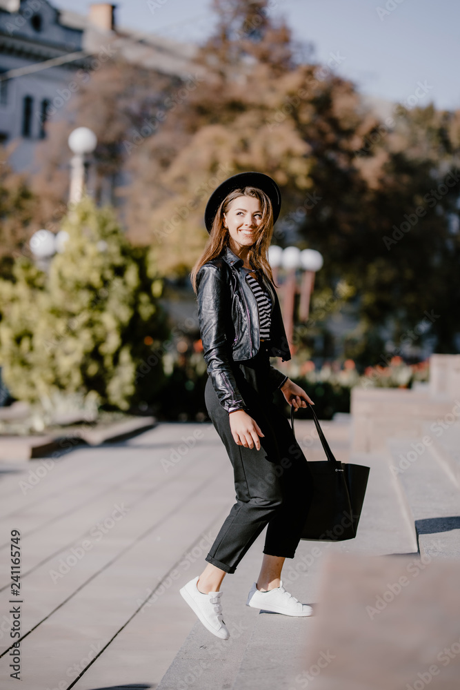 Fototapeta premium Young pretty woman walking up the stairs in the city outdoors