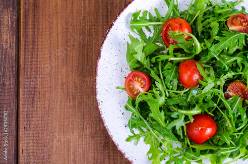 Plate with light dietary salad of arugula and cherry tomatoes