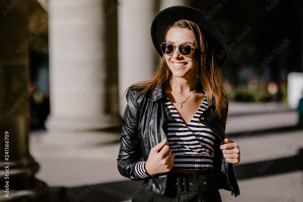 Street portrait of a young beautiful woman wearing stylish clothes, trendy hat and sunglasses.