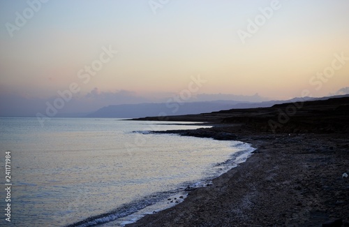 Sunset and dusk at coast of Dead Sea  rocks and salty beach with geologic rock and salt layers  Israel