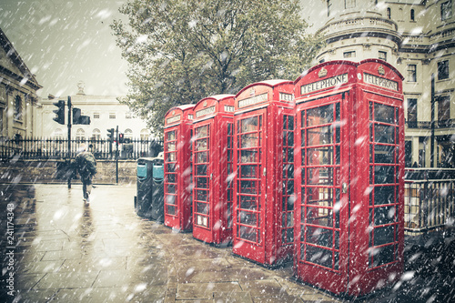 Canvas Print Winter London street scene with iconic red phone booths with snow falling