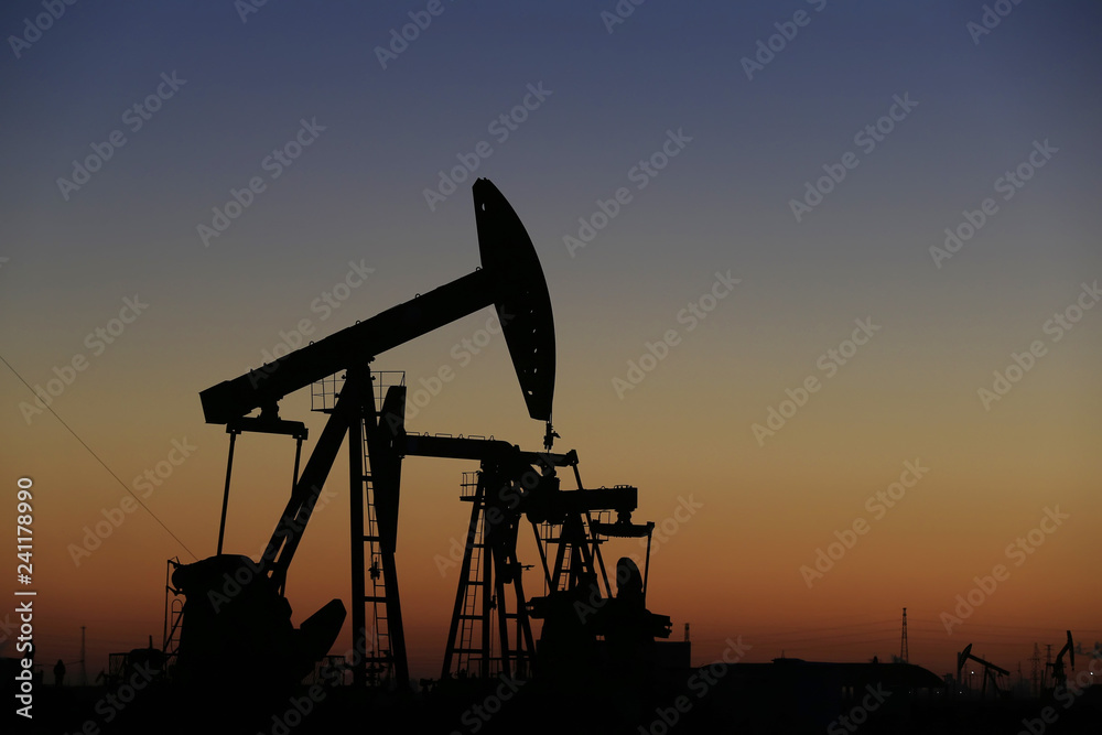 The pumping unit is at work in the evening of the oilfield The pumping unit is at work in the evening of the oilfield
