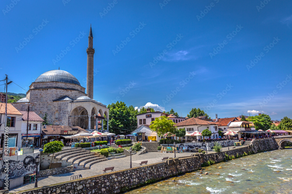 Naklejka premium Prizren, Kosovo - May 30th 2018 - A huge mosque with a river flowing in front of it in downtown Prizren in a blue sky day in Kosovo