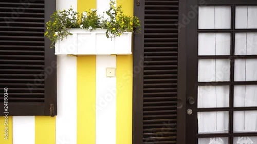 Closeup facade of house in Costa Nova village. Panning on wooden brown window with cute curtains and door on yellow building in Costa Nova, Portugal