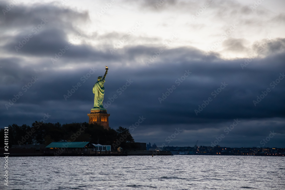 Statue of Liberty during a vibrant cloudy sunrise. Taken in Jersey City, New Jersey, United States.