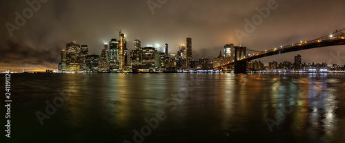 Panoramic view of the Downtown Manhattan and Brooklyn Bridge during a foggy night. Taken in New York, NY, United States.