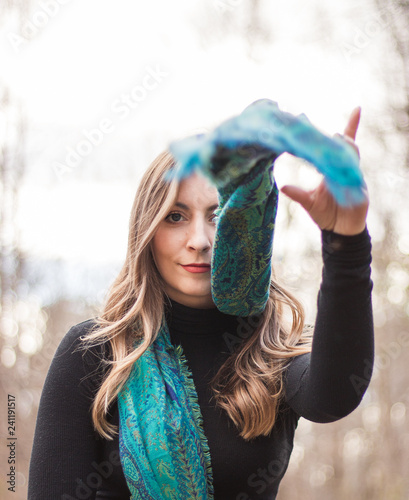 Obraz na plátně Smiley blonde young adult with blue eyes and black top wearing blue scarf in the