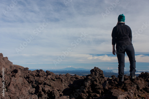 A woman hiker looking at Mount Taranaki in the distance from the Tongariro Great Walk in the North Island in New Zealand