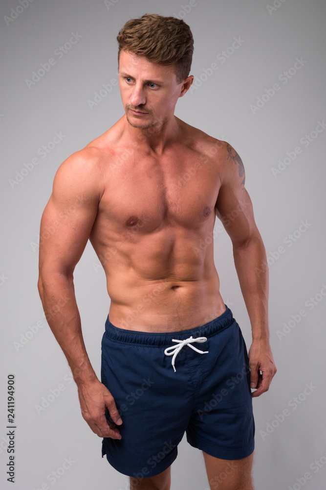 Muscular handsome bearded man shirtless against white background