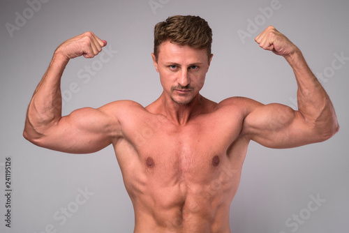 Muscular handsome bearded man shirtless and flexing muscles