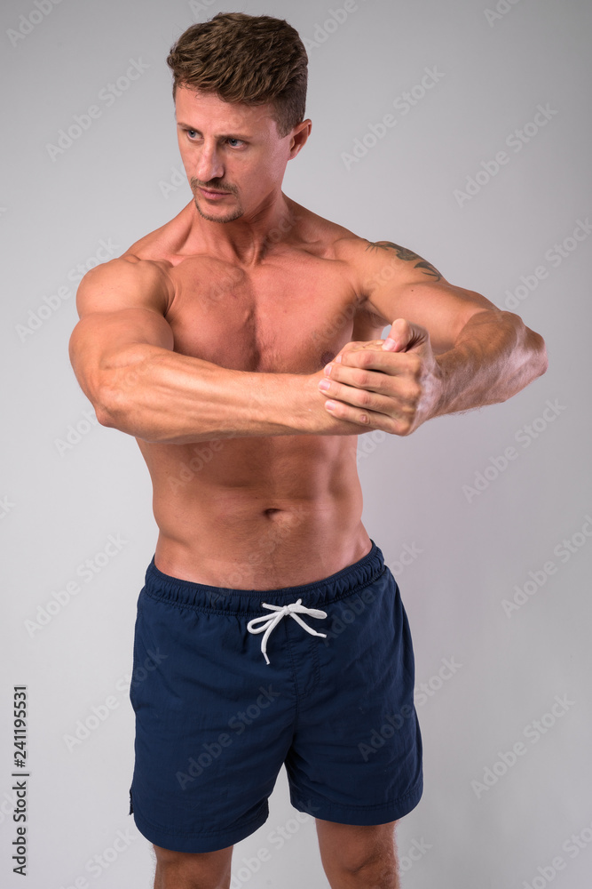 Muscular handsome bearded man shirtless against white background