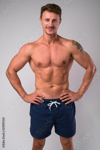 Happy muscular bearded man shirtless smiling against white background © Ranta Images
