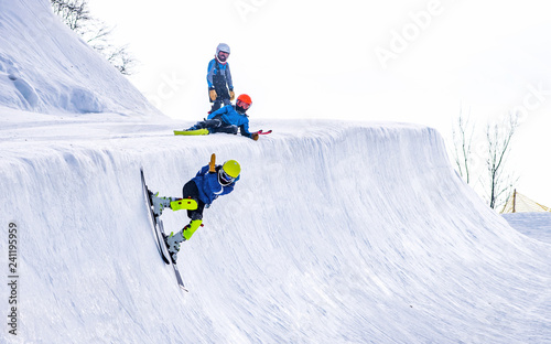 People are enjoying half-pipe skiing / snowboarding 