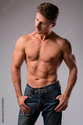 Muscular handsome bearded man shirtless against white background