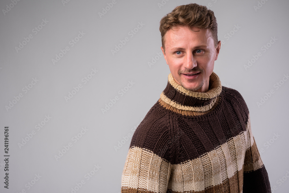 Fototapeta premium Happy bearded man wearing turtleneck sweater thinking and looking away