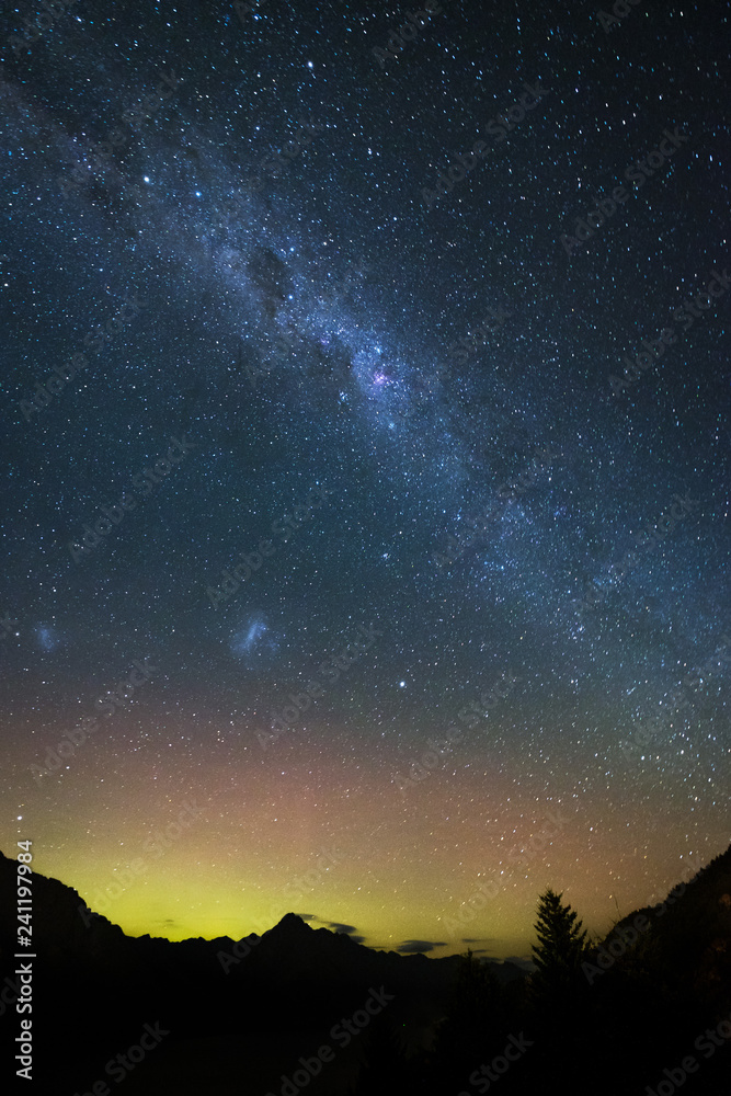 Spectacular view as aurora and milky way galaxy lights up the sky. When particles from a solar storm reached our Earth, it creates an array of colored lights as they hit the atmosphere. Spectacular view as aurora and milky way galaxy lights up the sky. When particles from a solar storm reached our Earth, it creates an array of colored lights as they hit the atmosphere.