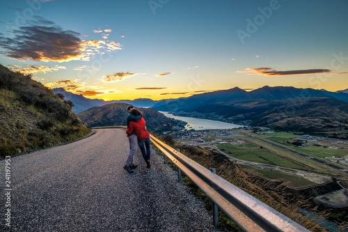 Couple enjoys beautiful queenstown scenery in New Zealand. Romantic couple goes on road trip. A pair of couple goes on honeymoon in natural landscape. Happiness image of a young couple. photo
