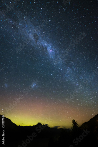 Spectacular view as aurora and milky way galaxy lights up the sky. When particles from a solar storm reached our Earth, it creates an array of colored lights as they hit the atmosphere.