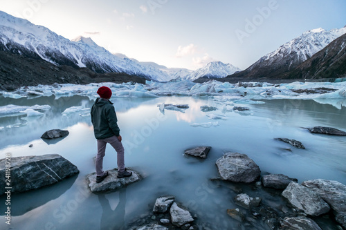 Person standing on ice lake and snow mountains at Tasman Lake, Aoraki Mount Cook National Park,New Zealand. photo