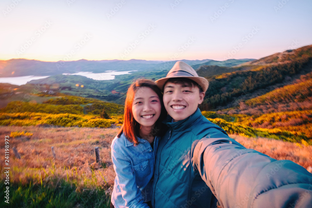 Couple enjoys beautiful Port Hills, Christchurch in New Zealand. Romantic couple goes on holiday. A pair of couple goes on honeymoon in natural landscape. Happiness image of a young couple.