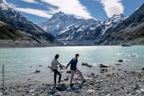 Couple enjoys beautiful scenery in New Zealand. Romantic couple holding hands. A pair of couple goes on honeymoon in natural landscape. Happiness image of a young couple exploring mount cook.