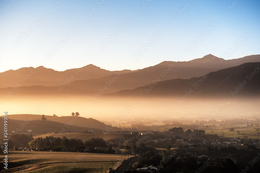 A brand new day arrives. As the sun shines through the low layer clouds, a heavenly golden light ray forms across the land. The atmosphere looks breathtaking. This image is suitable for travel use.