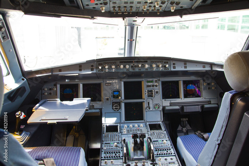 Airplane's cockpit with front,overhead and pedestrian panel taken on ground at dusk with concrete pavement in background.