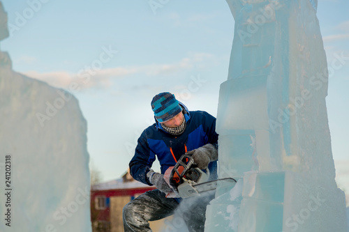 The sculptor cuts a Santa gasoline saw out of an ice block