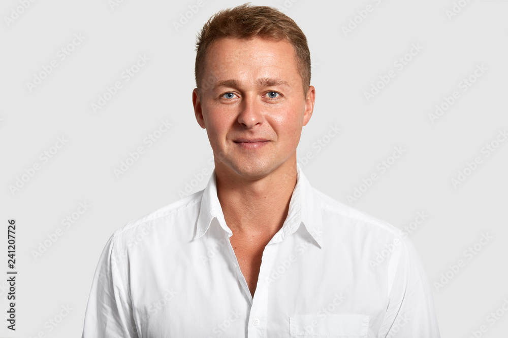 Portrait of handsome blue eyed man with confident expression, wears white shirt, looks at camera, being prosperous businessman, poses indoor. Masculinity concept. Attractive elegant male teacher Portrait of handsome blue eyed man with confident expression, wears white shirt, looks at camera, being prosperous businessman, poses indoor. Masculinity concept. Attractive elegant male teacher