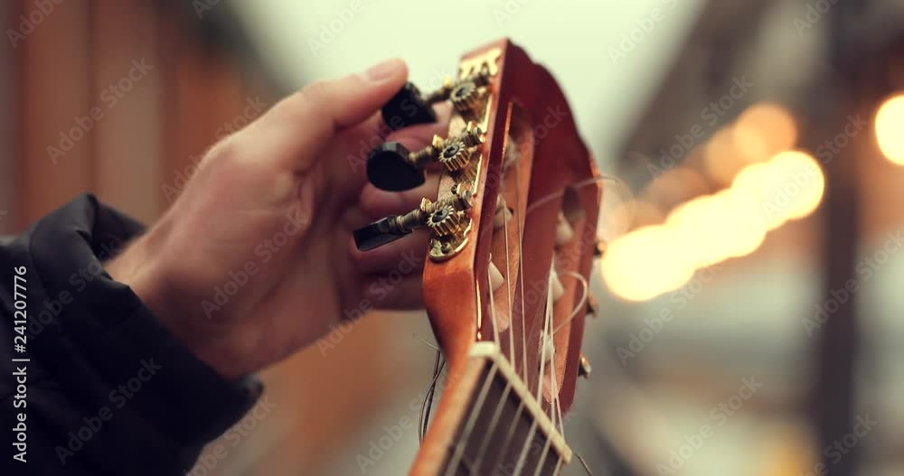 Close up 4k Footage of hand tune his guitar on the street with blurred background lights. - Video