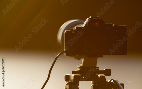 Camera DSLR set on tripod capturing sunset on beach. photo