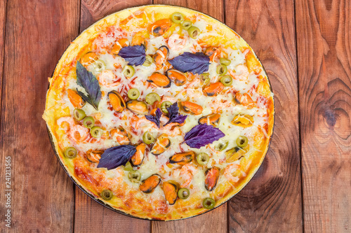 Cooked round pizza with seafoods on rustic wooden table