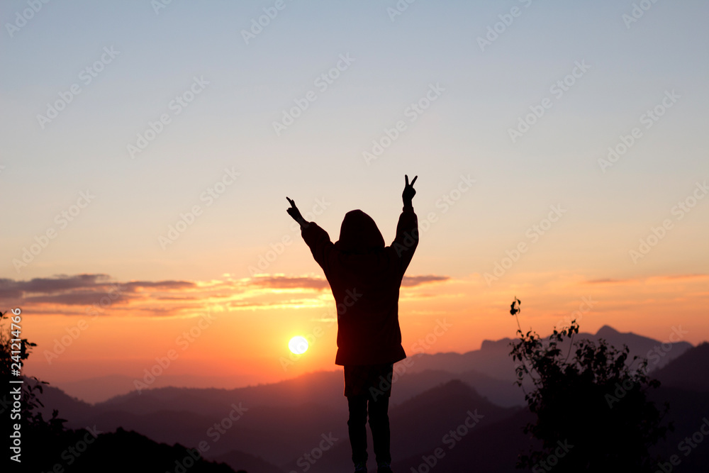 Silhouette child hands shape sign and sunset sky