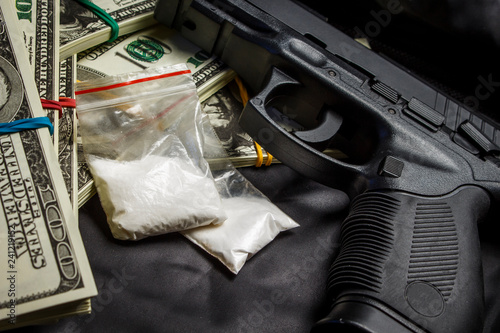 Drug in the form of white powder in plastic bags on packs of dollars with a gun